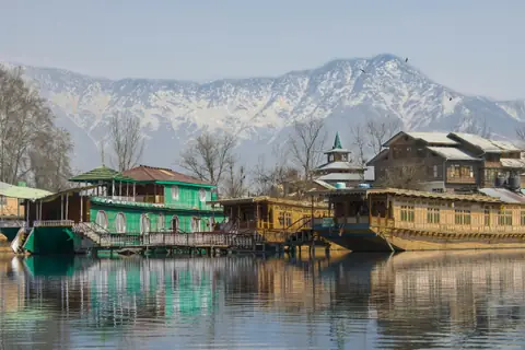 Carved wooden houseboats on Dal Lake with snow peaks behind Carved wooden houseboats on Dal Lake with snow peaks behind