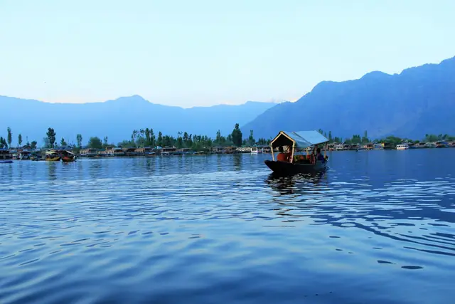 A shikara crossing the calm water of Dal Lake A shikara crossing the calm water of Dal Lake