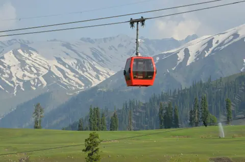A red gondola cabin rising over the Gulmarg meadows A red gondola cabin rising over the Gulmarg meadows