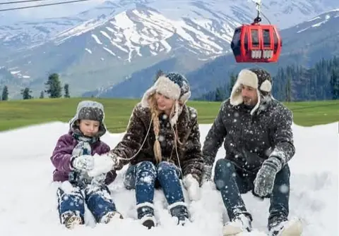 A family playing in the snow below the Gulmarg gondola