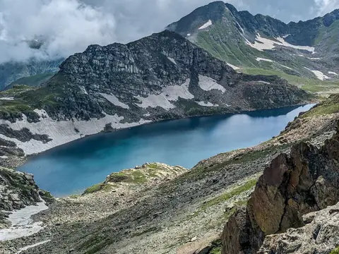 A deep blue alpine lake between green ridges on the Kashmir Great Lakes trek